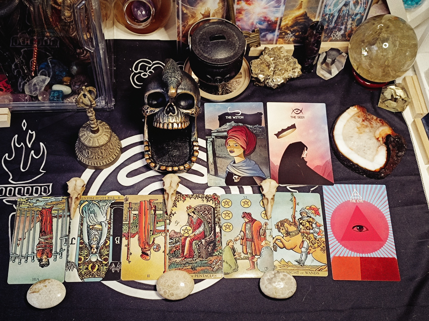 Six-card tarot and oracle verdict spread arranged with crystals, bells, skull imagery, and ritual tools