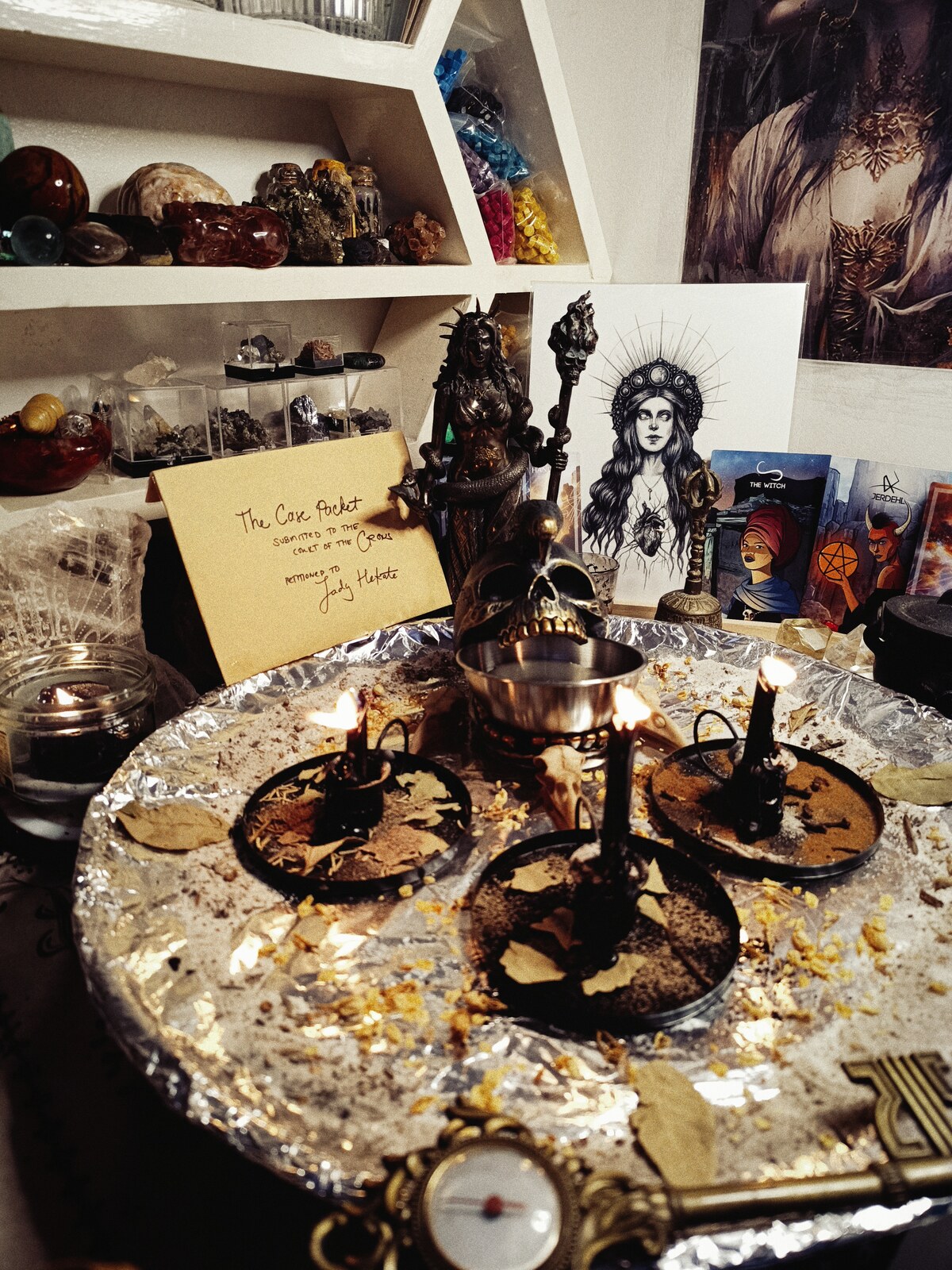 The Court of the Crows justice altar with three burning petition candles, Hekate imagery, herbs, and the client case packet