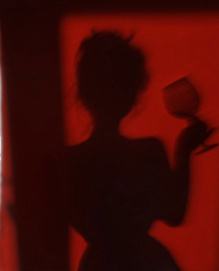 A red shadow silhouette of a woman holding a rose