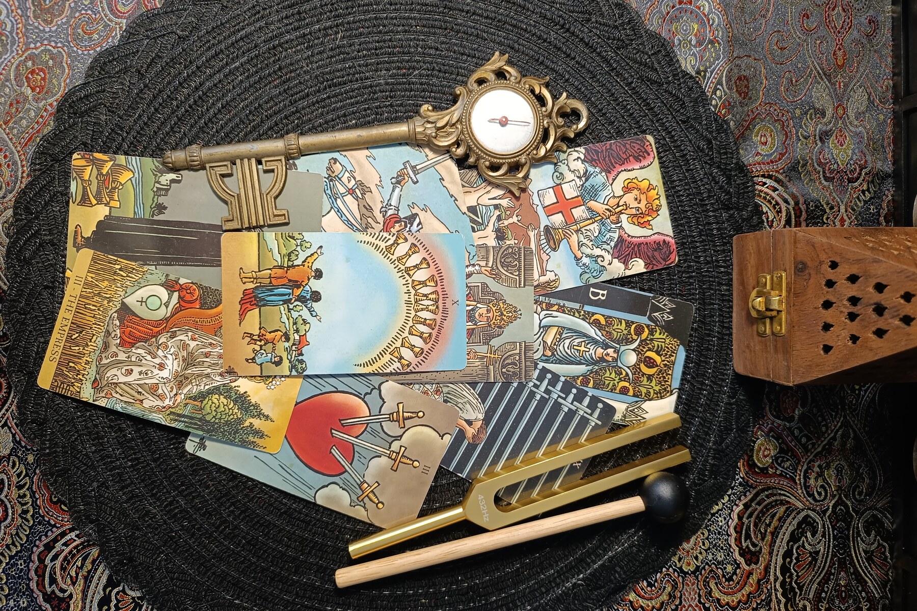 Tarot cards, a brass key, and tuning forks arranged for The Future Has Strange Rooms