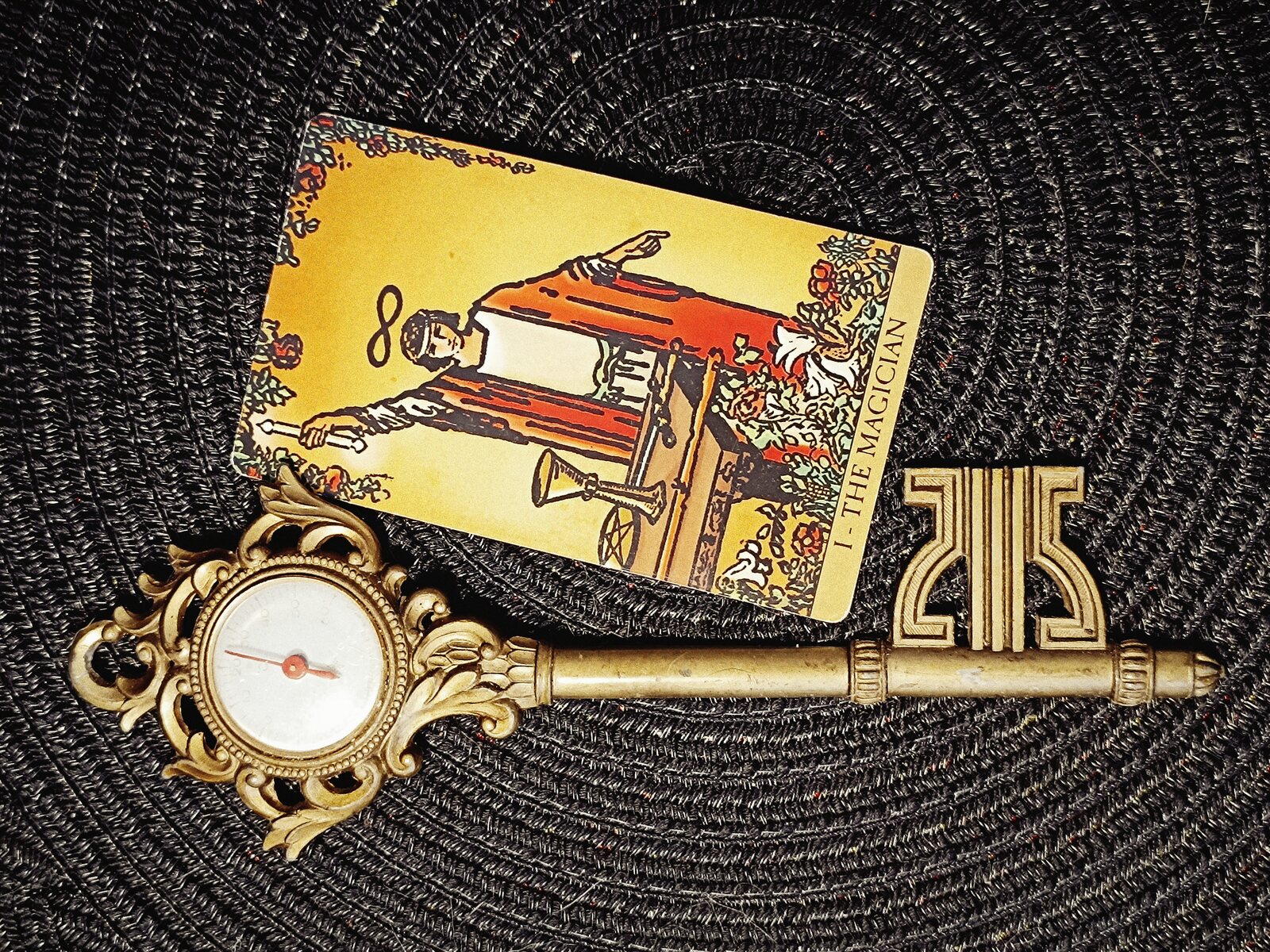 The Magician Tarot card beside an ornate brass key