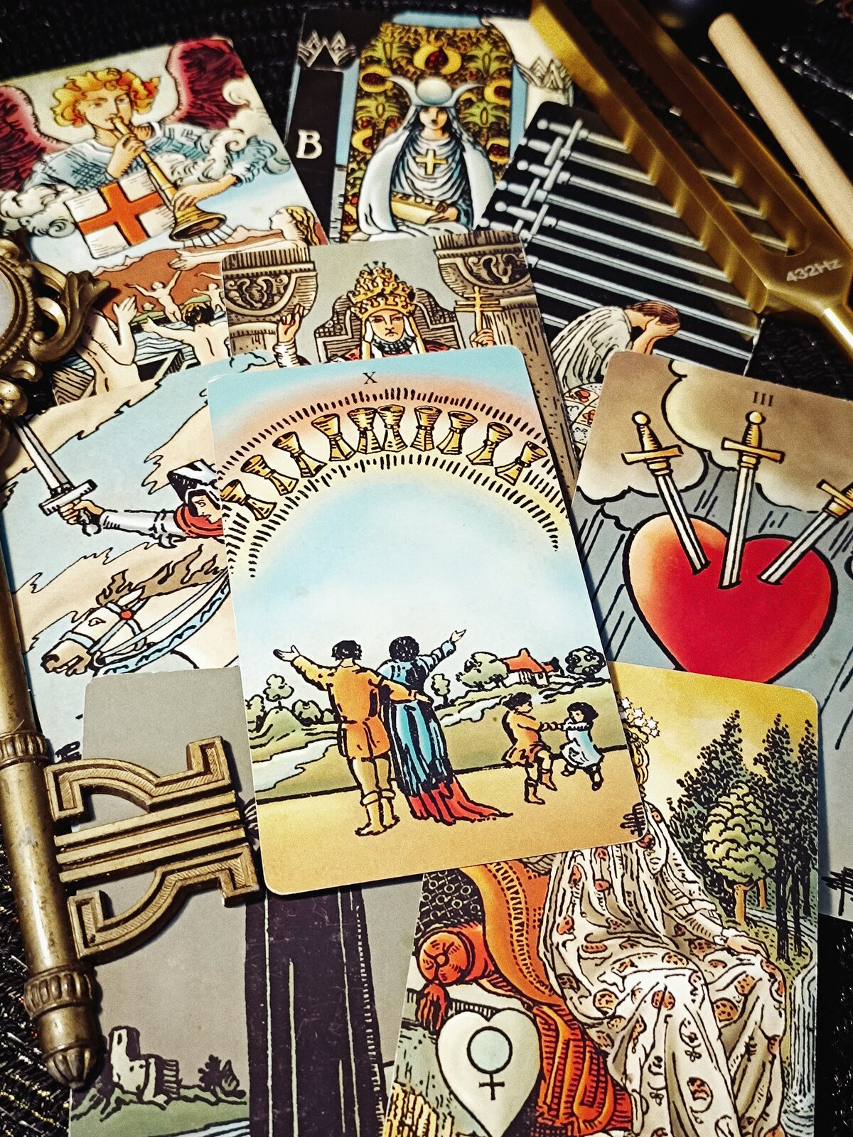 A close Tarot spread with the Ten of Cups, an ornate brass key, and tuning forks