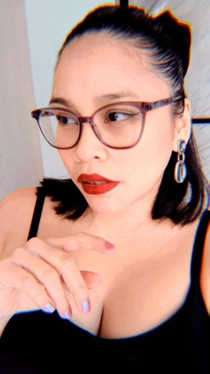 Portrait of Madame RBerry wearing glasses, red lipstick, and silver earrings
